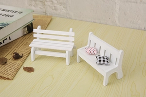 Miniature white wooden bench with decorative fabric pillows in a warm retro landscape scene