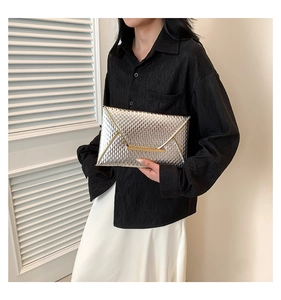 Detail of silver envelope clutch bag with mesh texture and gold metallic trim