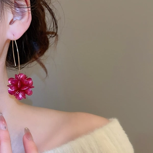 Dettaglio degli orecchini a fiore magenta indossati da una modella con luce morbida