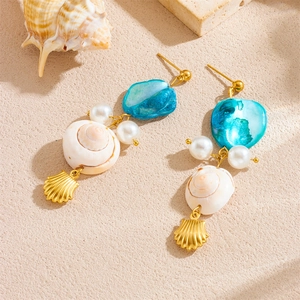 Golden sea shell earrings with blue shell slices and white pearls on sand background