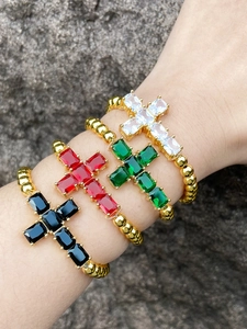 Detail of four gold beaded cross bracelets featuring black red emerald and white zircon