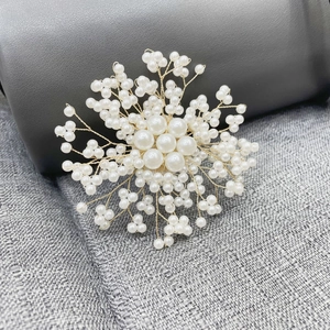 Detail of handcrafted gold wire snowflake brooch with elegant white pearls on gray fabric