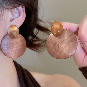 Macro shot of large round wooden drop earrings with amber resin beads and metal accents