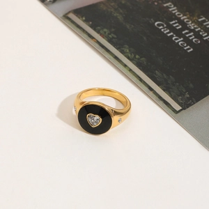 Close-up of golden ring featuring black enamel circle and a heart-shaped zircon stone