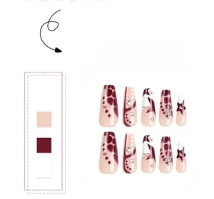 Détail de faux ongles ballerine rouge vin et beige avec motifs étoiles et strass