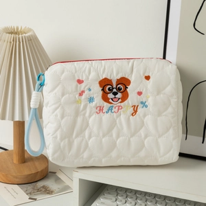 Close-up of white quilted makeup bag with heart texture and cute embroidered puppy