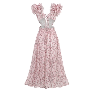 Détail de robe longue fleurie avec dos nu noué et manches à volants sur fond rose