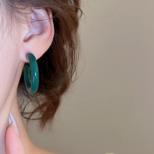 Gros plan d'un modèle portant des boucles d'oreilles créoles en acrylique vert foncé en C