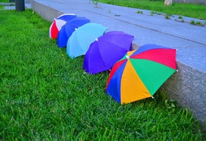 Detailed row of colorful umbrella hats with protective tips on green grass