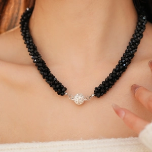 Detailed macro view of black faceted beaded necklace with a crystal-encrusted magnetic clasp