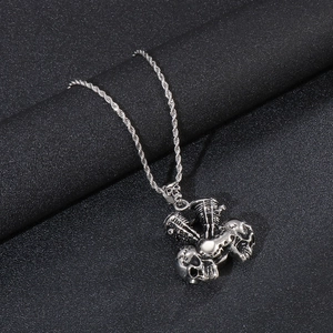 Detail of silver skull piston pendant with a braided rope chain on black texture