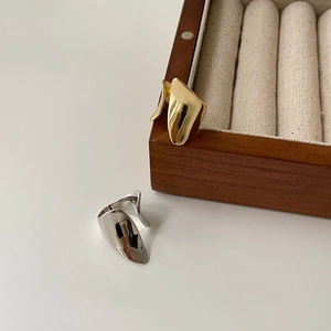Irregular shield-shaped opening rings in gold and silver finish on a wooden box