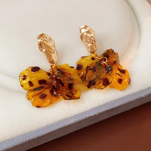 Detail of gold textured stud earrings with amber resin flower petals on a soft display pad