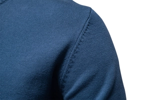 Gros plan sur la maille fine et les coutures renforcées de l'épaule du pull bleu marine