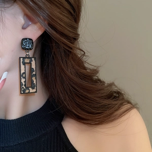 Gros plan d'un modèle portant des boucles d'oreilles léopard rectangulaires avec cadre doré