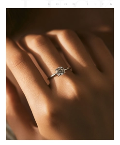 Artistic close-up of a pear-shaped moissanite ring on model hand with warm lighting