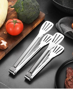 Close-up of slotted stainless steel food tongs on a kitchen counter for BBQ use