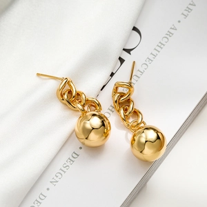 Elegant gold-plated ball drop chain earrings displayed on white fabric and art book