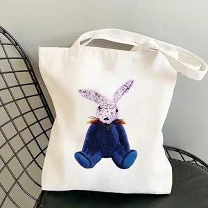 Creative bear and rabbit print on white canvas tote bag resting on metal mesh chair