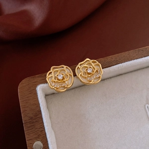 Macro shot of camellia stud earrings with sparkling zircon centers and gold hollow petals