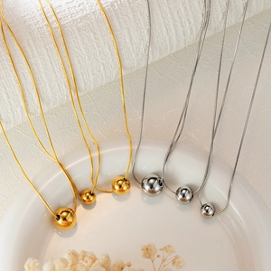 Minimalist 18K gold and silver stainless steel ball pendant necklaces set on white plate