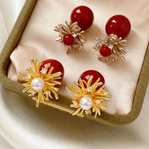 Close-up of zircon-inlaid flower earrings with large red resin beads on satin fabric