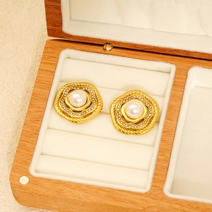 Golden flower earrings with pearl and rhinestones in a wooden jewelry display case