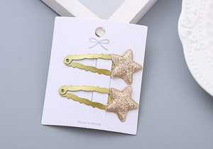 Close-up of golden glitter star hair clips on a card display for little girls