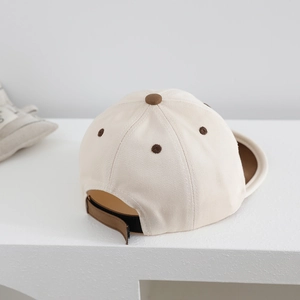 Detailweergave van de beige babyhonkbalpet met verstelbare bruine klittenbandsluiting en stof