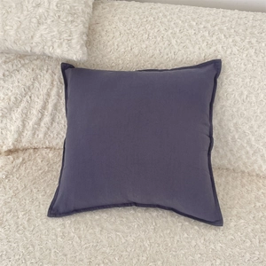Detail of dark blue-grey throw pillow case with high-quality seam edge on cream plush fabric