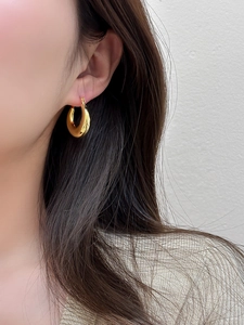 Close-up of polished gold round hoop earring worn on model for a minimalist jewelry look