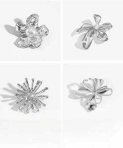 Detailed macro view of four silver geometric flower brooches with white pearl center inlay
