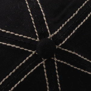 Macro detail of black cotton baseball cap top with contrast stitching and button