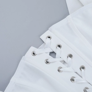 Close-up of metal eyelets and lacing details on white corset top fabric texture