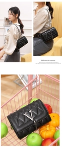 Detailed view of quilted black leather crossbody bag with V-shaped metal buckle and chain