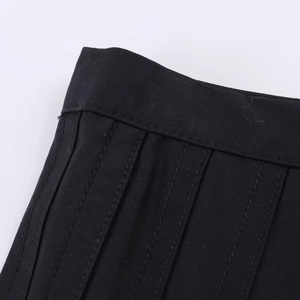 Vue macro d'une jupe midi plissée noire montrant les coutures précises et la texture du tissu