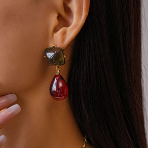 Gros plan de boucles d'oreilles géométriques en résine bordeaux et marron doré chic