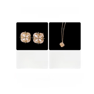 Macro view of clover jewelry set with crystal and pearl details on black background