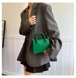 Detailed view of the green square crossbody bag with dual top handles on a model