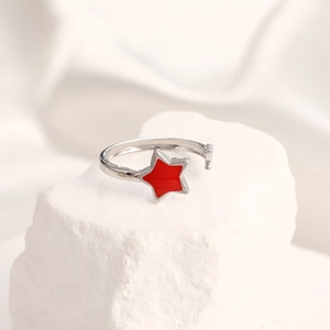 Detail shot of a silver adjustable ring featuring a glossy red star on a stone surface
