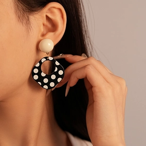Close-up of vintage black and white polka dot square drop earrings on a model