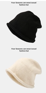 Detail of knit rolled-edge hats in black and off-white colors with thick wool texture