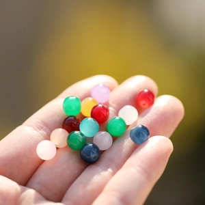 Close-up of colorful 8mm faux jade glass beads held in hand for DIY jewelry making