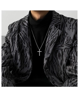 Silver cross pendant necklace styled on a model wearing a grey animal print blazer jacket