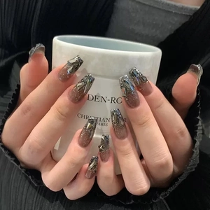 Macro detail of gradient coffee-colored nails with silver rhinestones and glitter accents