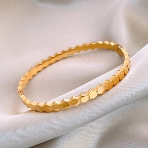 Macro detail of golden honeycomb titanium steel bracelet on champagne silk fabric