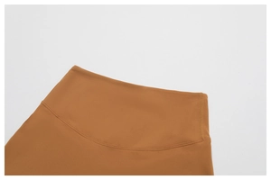 Detailed close-up of high-waisted stitching and smooth fabric on caramel yoga pants