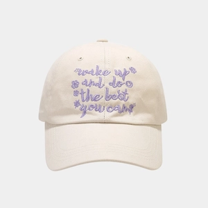 Detail of vintage beige baseball cap featuring purple letter embroidery and cotton texture