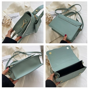 Detail view of mint green pleated handbag showing stitching, magnetic buckle and interior