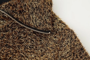 Close-up of golden metallic fringe fabric and silver metal zipper on bomber jacket